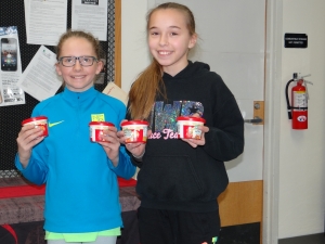 two girls holding canned goods